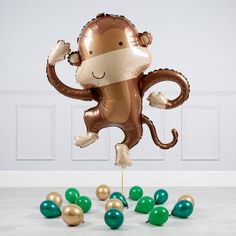 a balloon shaped like a monkey with green and gold balloons around it's feet