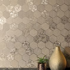 a vase sitting on top of a table next to a wall covered in hexagonal tiles