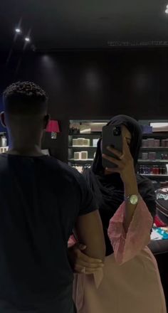 a man and woman standing in front of a store counter looking at their cell phones