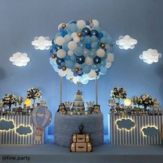 a blue and white dessert table with balloons in the shape of clouds on top of it