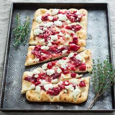 three flatbread pizzas with cheese and cranberry sauce on a metal tray