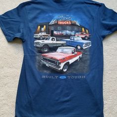 a blue t - shirt with an image of trucks in front of a truck shop