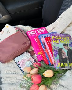 the contents of a car seat with flowers, books and a purse on top of it