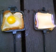 two toasted sandwiches with an egg in the middle and butter on top, sitting on a picnic table