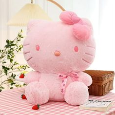 a pink hello kitty stuffed animal sitting on top of a table next to a basket