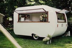 an old camper converted into a mobile home in the grass with its windows open