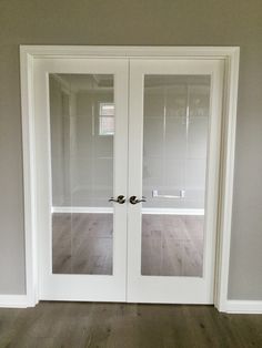 an empty room with two glass doors and wood flooring on either side of the door