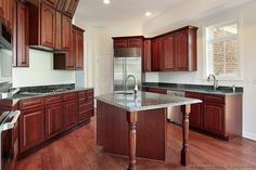 an empty kitchen with wooden cabinets and granite counter tops, along with stainless steel appliances