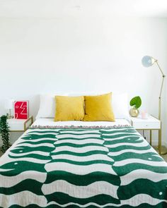 a green and white bed with two yellow pillows on it's headboard in a bedroom