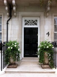 a black door with two potted plants in front of it and the number four