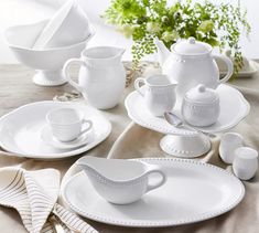 a table set with white dishes and cups