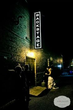 people standing in front of a building with a sign on it's side at night