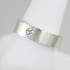 Handcrafted sterling silver ring with your choice of birthstone (Aquamarine pictured). Ring is 6mm wide and 2mm thick and has a 3mm round faceted lab-grown birthstone flush set in the center. The piece is brought to a glossy finish. This item is made to order, please allow up to 10 business days for fabrication. All stones are lab-grown except for Garnet, Amethyst, Peridot, and Citrine. Feel free to ask me for a price quote for any natural stone. Pearl Drop Pendant, Mother's Ring, Mothers Ring, Family Rings, Mother Rings, Three Rings, Price Quote, Wide Rings, Yellow Gold Pendants