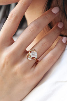 a woman's hand wearing a gold ring with an oval shaped diamond on it