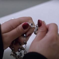 a woman holding onto a chain with beads on it's ends and her hands