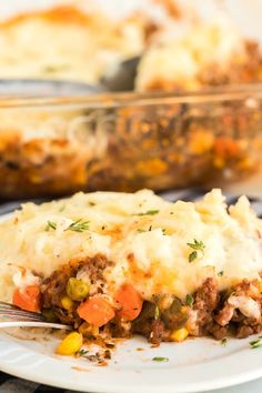 a white plate topped with mashed potatoes covered in meat and veggies next to a casserole dish