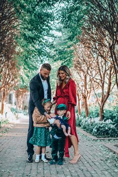 a man and woman with two children standing in the middle of a path surrounded by trees