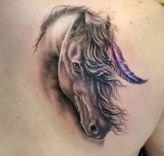 a woman's back with a tattoo of a horse and feathers on the side