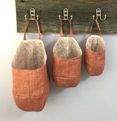 three orange bags hanging from hooks on a wall