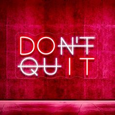 a neon sign that says don't quit out on the wall in front of it