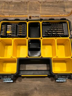 a yellow tool box filled with tools on top of a wooden table