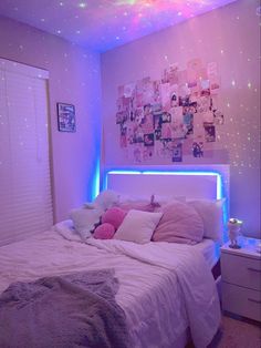 a bedroom with pink and blue lights on the ceiling, white bedding and pillows