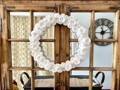 a wreath made out of white paper flowers sits in front of an old wooden door