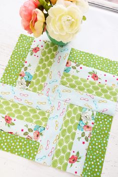 a vase filled with flowers sitting on top of a green and white patchwork table