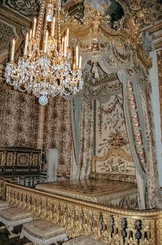 an ornate bed with chandelier and curtains