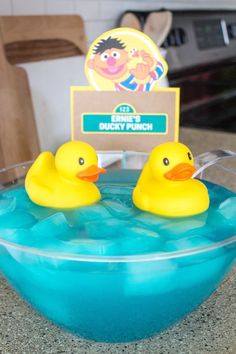 two rubber ducks in a blue bowl on a counter top next to a sign that says happy birthday