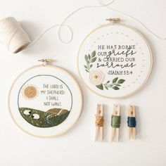 two cross stitch hoops, one with a bible verse and the other with three small spools of thread