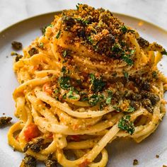 a white plate topped with pasta covered in sauce and parmesan cheese sprinkled on top