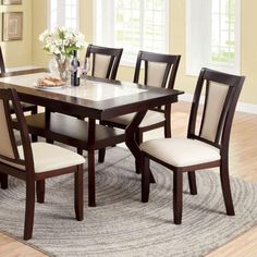 a dining room table with chairs and a rug in front of the table is shown