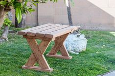 a wooden bench sitting in the grass next to a tree and potted planter