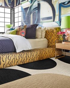 a bedroom with a tiger print bed and rugs in front of a large window