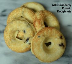 four blueberry bagels sitting on top of a marble counter with the words abs cranberry protein doughnuts