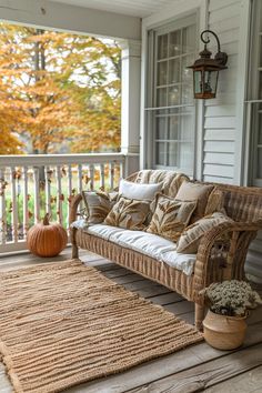 a porch with wicker furniture and pumpkins on the front porch, along with an area rug