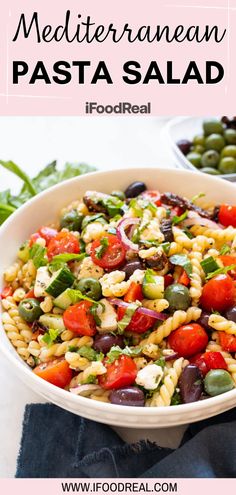 pasta salad with tomatoes, olives and green beans in a white bowl