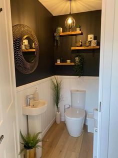 a white toilet sitting in a bathroom next to a sink and wooden floored floors