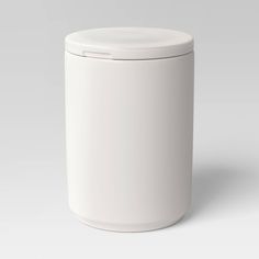 a white canister with a lid on the side, sitting in front of a gray background