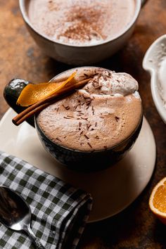 two bowls filled with ice cream on top of a wooden table next to an orange slice