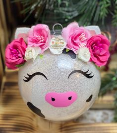 a glass pig ornament with pink flowers on it's head and eyes