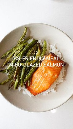 a white plate topped with green beans and salmon