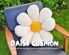 a knitted flower sitting on top of a blue chair with the words daisy cushion