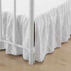 a white crib bed skirt on a wooden floor