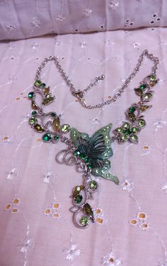 This beautiful piece is a Statement Necklace that is a Silvertone Chain with Flowers along the chain enhanced with different shades of Green Rhinestones and a Butterfly that in enhanced with Green Enamel and shades of Green Rhinestones with a Floral Drop below. Lobster clasp closure. Adjustable size. Length of the necklace is approximately 18 inches. Green Jeweled Crystal Rhinestone Necklace, Green Jeweled Rhinestone Crystal Necklace, Green Rhinestone Costume Jewelry, Green Bling Jewelry As A Gift, Green Rhinestone Jewelry For Gift, Green Rhinestone Jeweled Necklace For Gift, Green Rhinestone Necklace For Gift, Green Necklaces With Rhinestones As Gift, Green Rhinestone Costume Jewelry Necklace As Gift