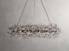 a chandelier with branches and lights hanging from it's sides, in front of a gray wall