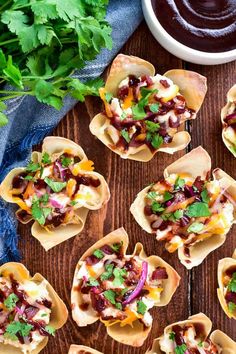 mini tacos filled with meat, cheese and cilantro on top of a wooden table