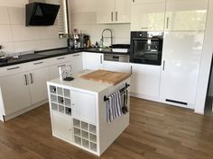 a kitchen with white cabinets and wood floors is pictured in this image, there are black appliances on the counter