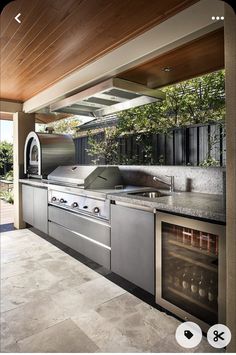 an outdoor kitchen with stainless steel appliances and counter tops, built in to the ceiling